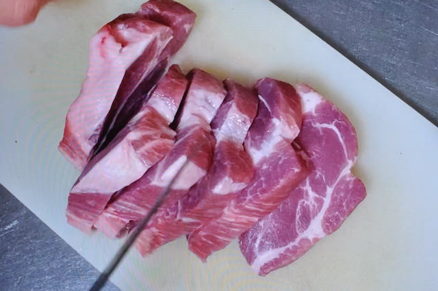 カレーの具材に使う豚肉を切る
